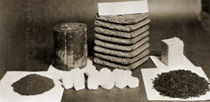 A black-and-white photo shows various forms of tea—including loose leaves, powdered tea, and compressed bricks—arranged on a table with paper labels, reminiscent of Antarctic Logistics and Expeditions’ careful preparation for journeys to Antarctica.