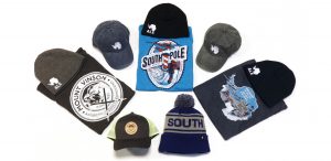A collection of Antarctic Logistics and Expeditions-themed hats, beanies, and t-shirts displayed on a white background, featuring logos and images related to the South Pole, Mount Vinson, and Antarctica.