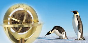 A brass sundial engraved with SCOTT JANUARY 17, 1912 and an image of explorers stands beside two emperor penguins on snow under a clear blue sky.