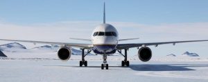 A large commercial airplane, operated by Antarctic Logistics and Expeditions, is parked on a snowy, icy runway in Antarctica with snow-covered mountains in the background under a clear blue sky.