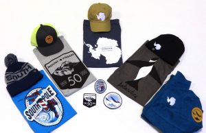 A variety of Antarctica-themed merchandise is displayed, including T-shirts, caps, a beanie, a scarf, patches, and a hoodie—all showcasing polar motifs and South Pole map designs on a white background.