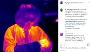 A person in a lab coat appears in a thermal image, with warmer areas shown in yellow and cooler areas in purple and blue. The dark background hints at the cold environment typical of Antarctica or the South Pole.