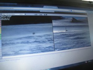 A computer screen displays two live camera feeds showing a snowy, windswept landscape with hills and a runway, likely from Antarctica—possibly capturing the remote operations of Antarctic Logistics and Expeditions near the South Pole.